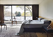 Maskulines Schlafzimmer mit Designklassikern und Glasfront