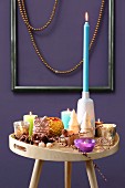 Colourful collection of candles on tray table in front of purple wall