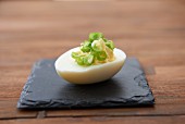 A devilled egg with spring onions