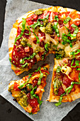 Pizza mit Tomaten, Käse und Pesto (angeschnitten)
