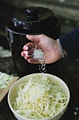 Salt being added to grated white cabbage