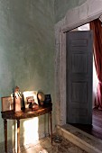 Delicate antique console table next to open double doors in rustic, Mediterranean interior