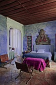 Rustikales mediterranes Schlafzimmer mit religiösem Gemälde an blaugetönter Wand, Doppelbett und Retro-Lederstühle