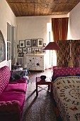 Pinkfarbenes Sofa gegenüber Tagesbett mit folkloristischer Decke in eklektischem Ambiente