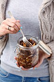 A woman holding a jar of herring with walnuts, pumpernickel and honey