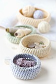 Pastel-coloured, crocheted baskets of haberdashery items