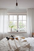 Off-white bedspread on bed below lattice window in rustic bedroom