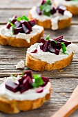 Slices of baguette topped with goat's cheese, marinated red turnip and parsley