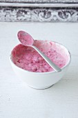 Raspberry yoghurt in a bowl with a spoon