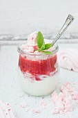 A glass filled with layers of yoghurt, raspberry & strawberry sauce and raspberry meringue