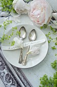 Place setting with silver spoons, name tag and peonies