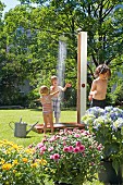 Children playing under outdoor shower in garden