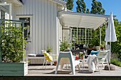 Outdoor easy chairs on wooden terrace outside white wooden house