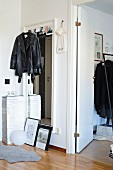 Schwarze Lederjacke an Wandspiegel in Diele neben offener Zimmertür