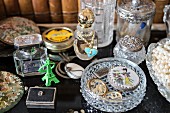 Vintage-style arrangement of perfume bottles and crystal dish of antique jewellery
