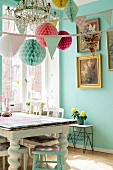 Dining room decorated with bunting and paper pompoms above vintage table with turned legs next to window