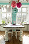 Holztisch mit massiven, gedrechselten Tischbeinen im Esszimmer, romantisch mit Papier-Pompons und Girlanden dekoriert