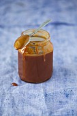 Homemade caramel sauce in a jar with a spoon
