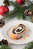 A slice of a traditional Polish poppy seed roll cake with icing, dried fruits and nuts