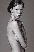 Young topless woman covering breasts with one arm