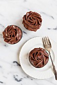 One chocolate and chai cupcake on a plate with a fork with two next to it