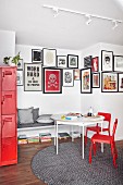 Red chairs at white table in front of fitted bench below gallery of pictures