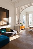 Modern sofa in living area in front of archway with lead-glazed surround and view into dining room