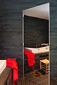 Mirrored door in bathroom with dark wall tiles