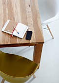 Notebook and smartphone on wooden table with shell chairs