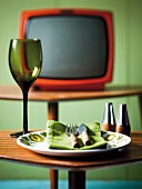 An empty plate with cutlery and a wine glass in front of the television