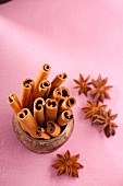 Cinnamon sticks and star anise on a pink surface