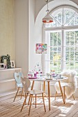 Frühstückstisch mit DIY-Deko in Pastelltönen vor Rundbogen-Sprossenfenster in Altbauwohnung