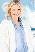 A young blonde woman wearing a denim shirt and a white fluffy jacket