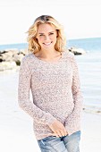 Junge blonde Frau in gestricktem Pulli und Jeans am Meer