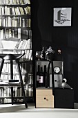 Wohnraum in Schwarz-Weiß mit Barschränkchen, Hocker und Fototapete mit Bücherregalmotiv