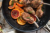 Roasted lamb chops with slices of blood orange and herbs in a pan