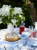Meringue cake with rhubarb and raspberry juice on a summer garden table
