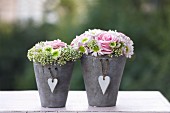 Flower arrangements with roses in grey pots with heart-shaped pendants
