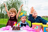 Three small children at a birthday party in a garden