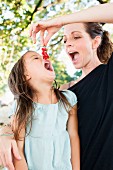 Mutter füttert Tochter mit roten Johannisbeeren