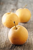 Three Nashi pears on a wooden surface