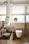 Waschtisch mit Waschschüssel und Badutensilien, Toilette vor Fenster in modernem, kleinem Bad