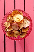 Homemade apple chips in a glass bowl (seen from above)