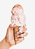A hand holding a melting ice cream