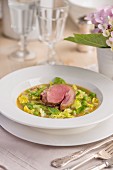 Pea soup with duck breast on a garden table