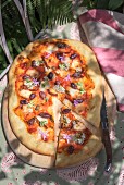 Focaccia with tomatoes, olives and edible flowers on the garden table