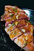 Raw leg of lamb with spices, herbs and garlic on a baking tray