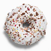 A doughnut with white icing and chopped chocolate beans