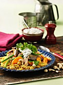 Lamb and chicken with yoghurt sauce, carrots and cashew nuts on a bed of rice