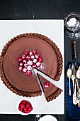 Gluten-free chocolate tart with raspberries and icing sugar